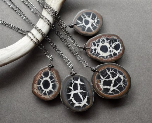 Five unique agate stone pendants on silver chains, showcasing intricate natural patterns, displayed on a gray background.
