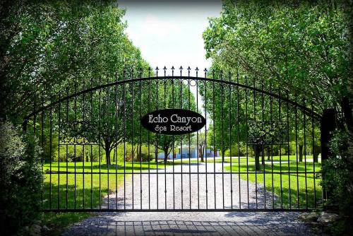 A wrought iron gate with "Echo Canyon Spa Resort" sign, surrounded by lush greenery and a gravel path.