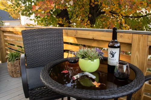 A cozy outdoor setting with a bottle of wine, two glasses, a succulent plant, and autumn leaves on a table.