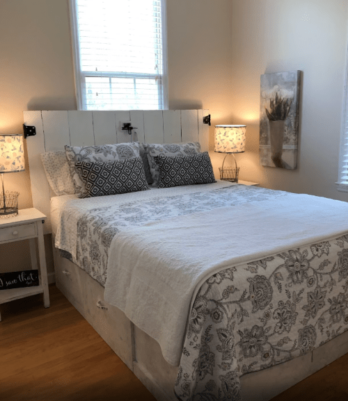 Cozy bedroom with a white bed, patterned pillows, and soft lighting from bedside lamps.