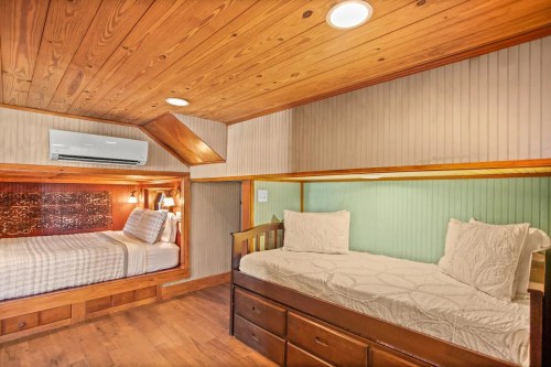Cozy bedroom with wooden accents, featuring a double bed and a twin bed in a warm, inviting space.