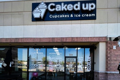 Sign for "Caked Up" featuring cupcakes and ice cream, with a storefront displaying various dessert options.