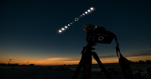 A camera on a tripod captures the phases of the moon against a twilight sky.