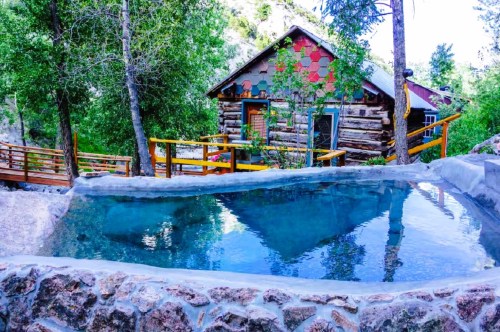 A historic log cabin with hot springs in Colorado tucked inside the forested area in the mountains