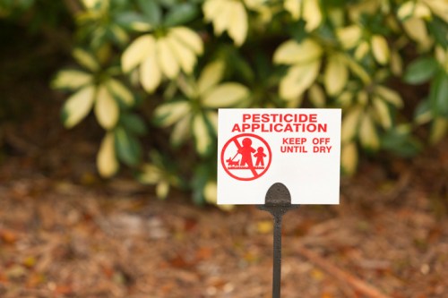 Sign warning against pesticide application, stating "Keep Off Until Dry," with a graphic of a child and adult.