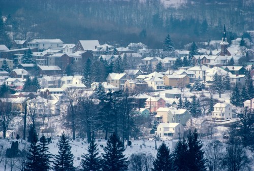 A snowy landscape featuring a small town with colorful houses and trees, blanketed in fresh snow.