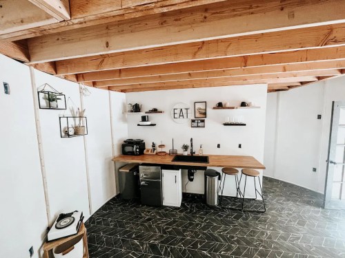 Modern kitchen with wooden beams, a countertop, appliances, and minimalist decor featuring an "EAT" sign.