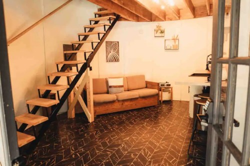 Cozy interior with a wooden staircase, sofa, and modern decor in a well-lit space.