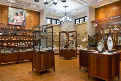 A well-lit museum display featuring wooden cabinets filled with various artifacts and decorative items.
