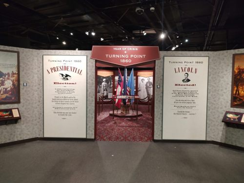 Exhibit entrance titled "Turning Point 1860" featuring historical displays and flags, highlighting the presidential election.