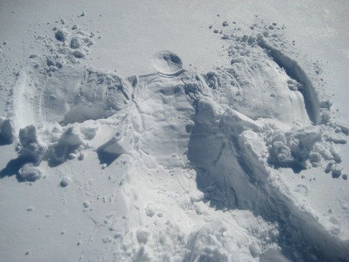 A snow angel created in fresh snow, with wings and a body outline visible in the white surface.
