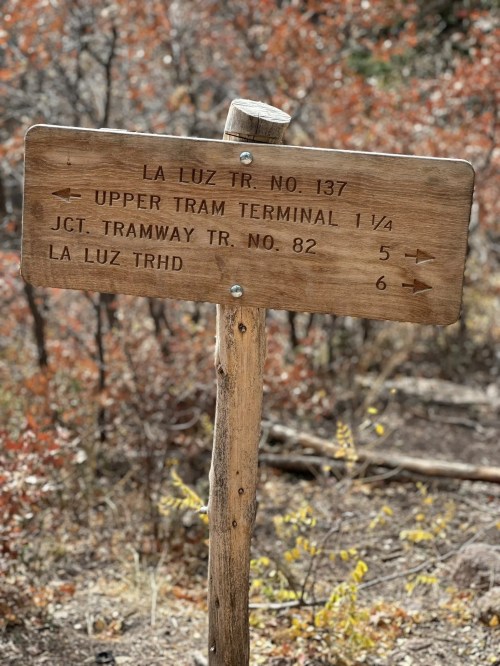 Wooden trail sign with directions: La Luz Trail No. 137, Upper Tram Terminal 1¼, Junction Tramway Trail No. 82, La Luz TH.