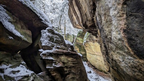 A narrow canyon with snow-dusted rocks and trees, creating a serene winter landscape.