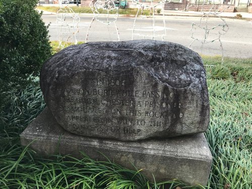 A large rock with an inscription commemorating a prisoner from Andersonville, Georgia, placed in a grassy area.