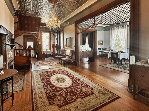 Elegant interior of a vintage home featuring ornate decor, a chandelier, and a cozy seating area with a patterned rug.