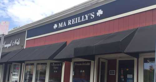 Exterior of Ma Reilly's, a storefront with a sign and awnings, featuring windows displaying various food items.