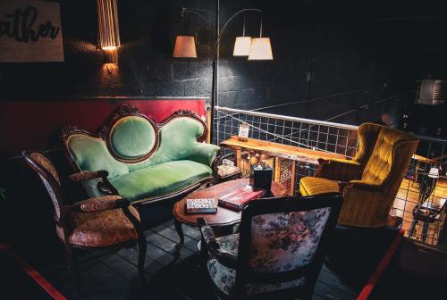 Cozy seating area with vintage green and yellow chairs, a wooden table, and warm lighting in a dimly lit space.
