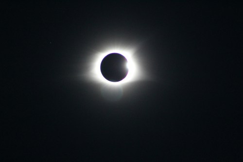 A solar eclipse with the moon partially covering the sun, creating a halo effect around the darkened center.