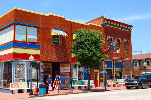 Colorful building facade featuring a comic book museum, with bright signage and a tree in front.