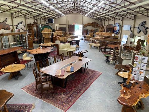 A spacious furniture showroom filled with wooden tables, chairs, and decor, showcasing various styles and designs.