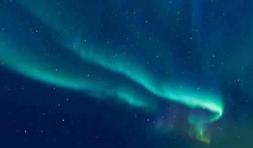 A stunning display of the aurora borealis with vibrant green and blue lights against a starry night sky.