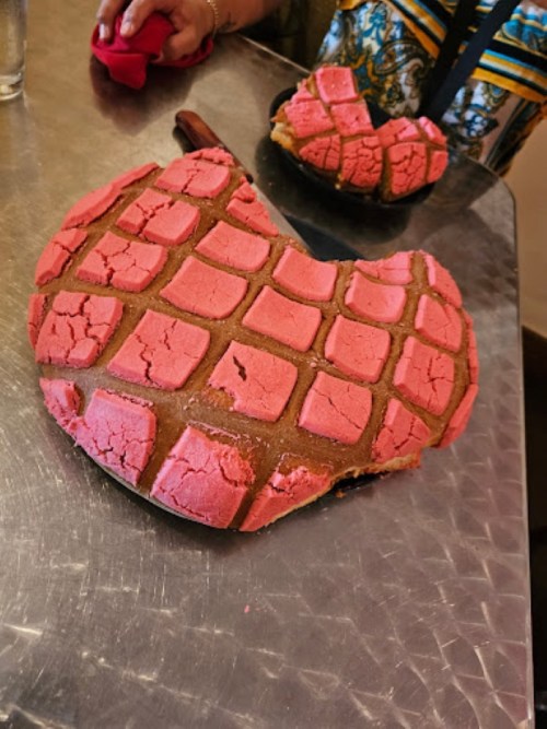A large, cracked pink dessert with a grid pattern, placed on a metal surface.