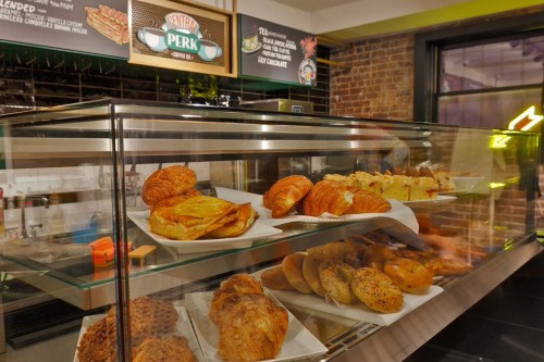 A display case filled with various baked goods, including croissants and pastries, in a cozy café setting.