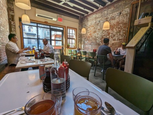 A cozy restaurant interior with exposed brick walls, tables, and patrons enjoying their meals.
