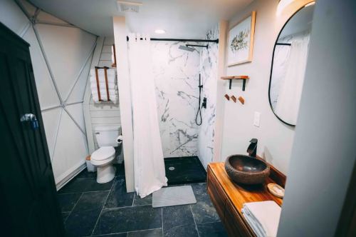 Modern bathroom featuring a shower with a curtain, a round mirror, a wooden vanity, and slate flooring.