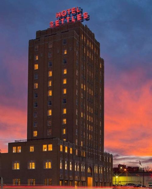 Historic Hotel Settles illuminated at dusk, with a vibrant sunset sky and glowing windows.