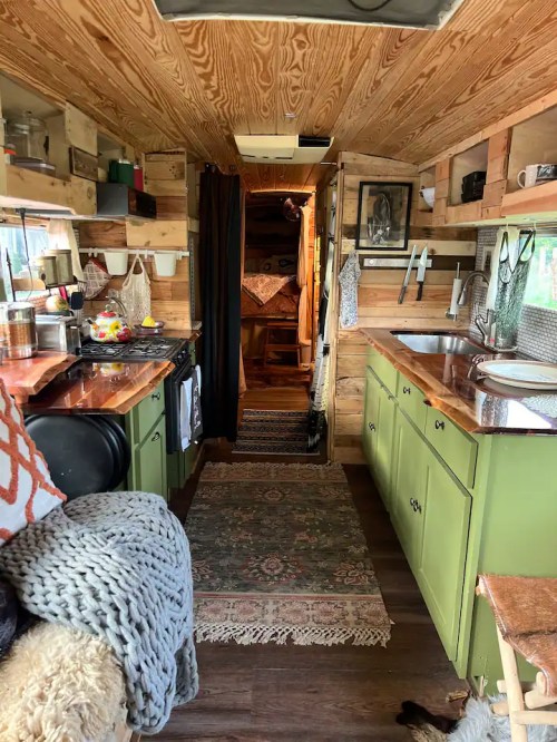 Cozy interior of a tiny home on wheels, featuring wooden walls, a kitchen area, and a warm, inviting atmosphere.