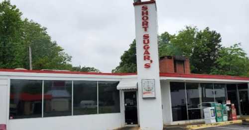 Exterior of Short Sugar's restaurant, featuring a tall sign, large windows, and a red and white color scheme.