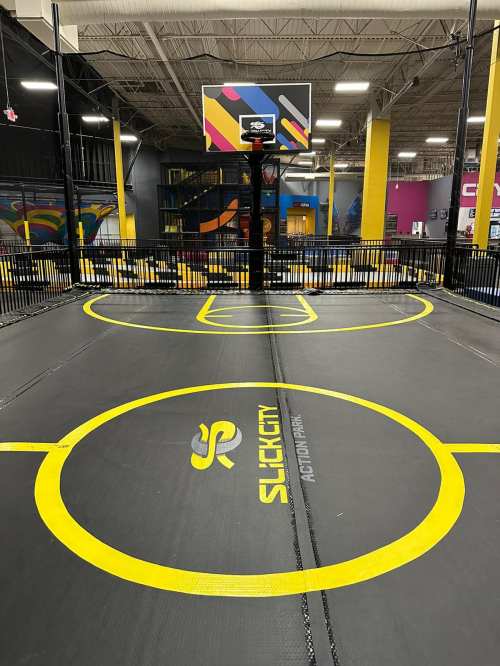 A vibrant indoor basketball court with a sleek design, featuring a hoop and colorful walls in the background.
