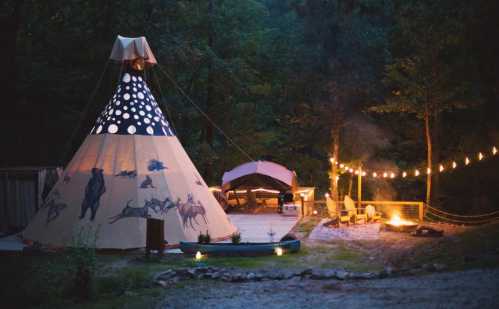 A cozy campsite at dusk featuring a teepee, string lights, a fire pit, and a wooden deck surrounded by trees.