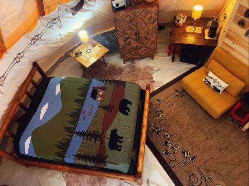 Cozy interior of a cabin with a log bed, patterned blanket, rug, and warm lighting.