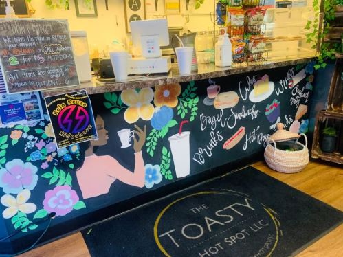 A colorful café counter with floral murals, a sign about drink refills, and a welcoming atmosphere.