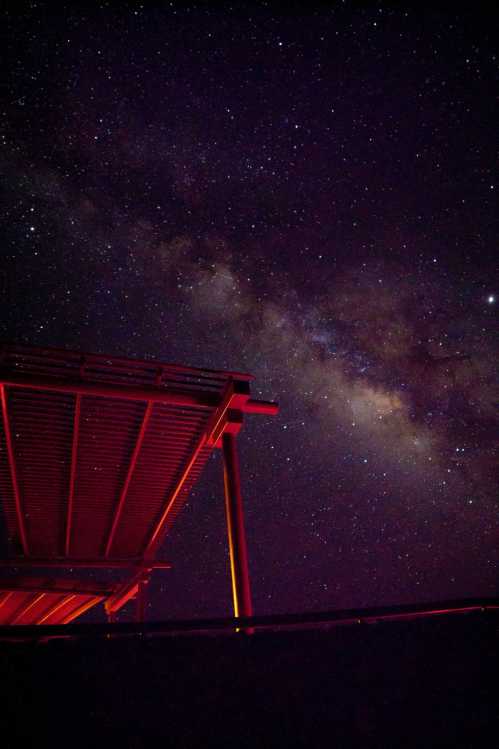 A starry night sky with the Milky Way visible above a silhouetted structure.