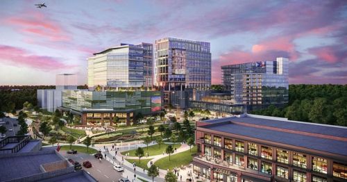 A modern urban development featuring glass buildings, green spaces, and a bustling street scene at sunset.