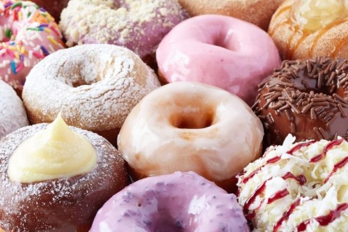 A colorful assortment of donuts with various toppings and glazes, including sprinkles, frosting, and powdered sugar.