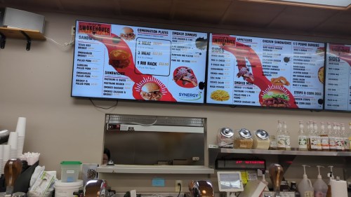 Menu board displaying various food options, including sandwiches, combination plates, and appetizers at a restaurant.