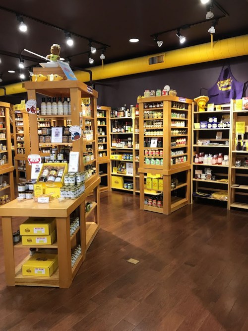 A brightly lit store interior with wooden shelves filled with jars and bottles of various products.