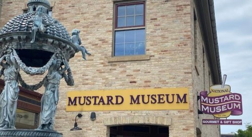Exterior of the National Mustard Museum, featuring a decorative fountain and a sign for the gourmet gift shop.