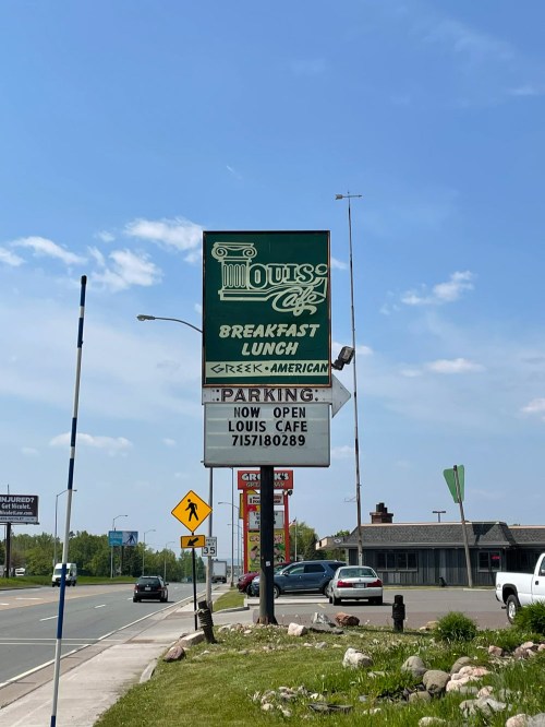 Sign for Louis Cafe, offering breakfast and lunch, with a note about parking and its recent opening.