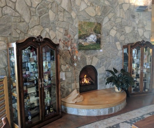 Cozy interior featuring stone walls, a fireplace, and glass display cabinets with decorative items.