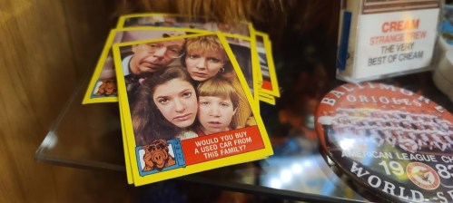 A display of vintage cards featuring a family with a humorous caption about buying a used car from them.