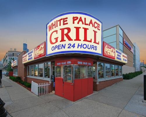 A brightly lit diner, White Palace Grill, with a large sign stating "Open 24 Hours" and Coca-Cola branding.