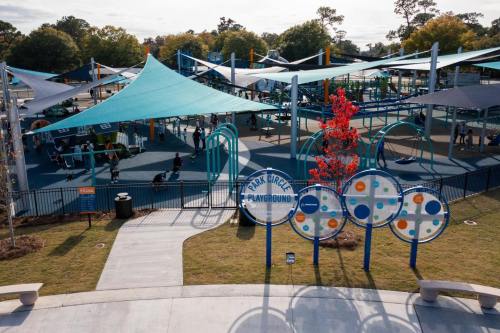 A vibrant playground with colorful canopies, featuring play structures and families enjoying the outdoor space.
