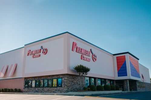 Exterior of Premier Cinemas building with a clear blue sky, featuring large signage and movie posters on display.