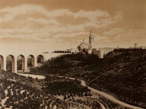 A sepia-toned landscape featuring a viaduct, hills, and a distant church or cathedral against a cloudy sky.