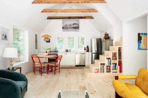 Bright, modern interior of a cozy kitchen and living area with wooden beams, a dining table, and colorful furniture.